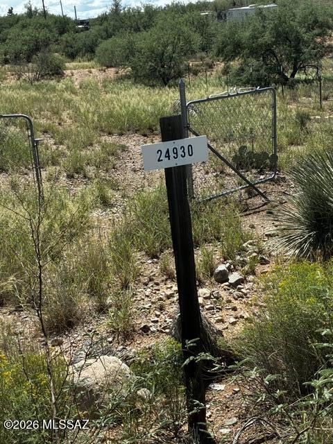 The gate at 24930 E Comanche Trail, with mesquite and open grassland beyond