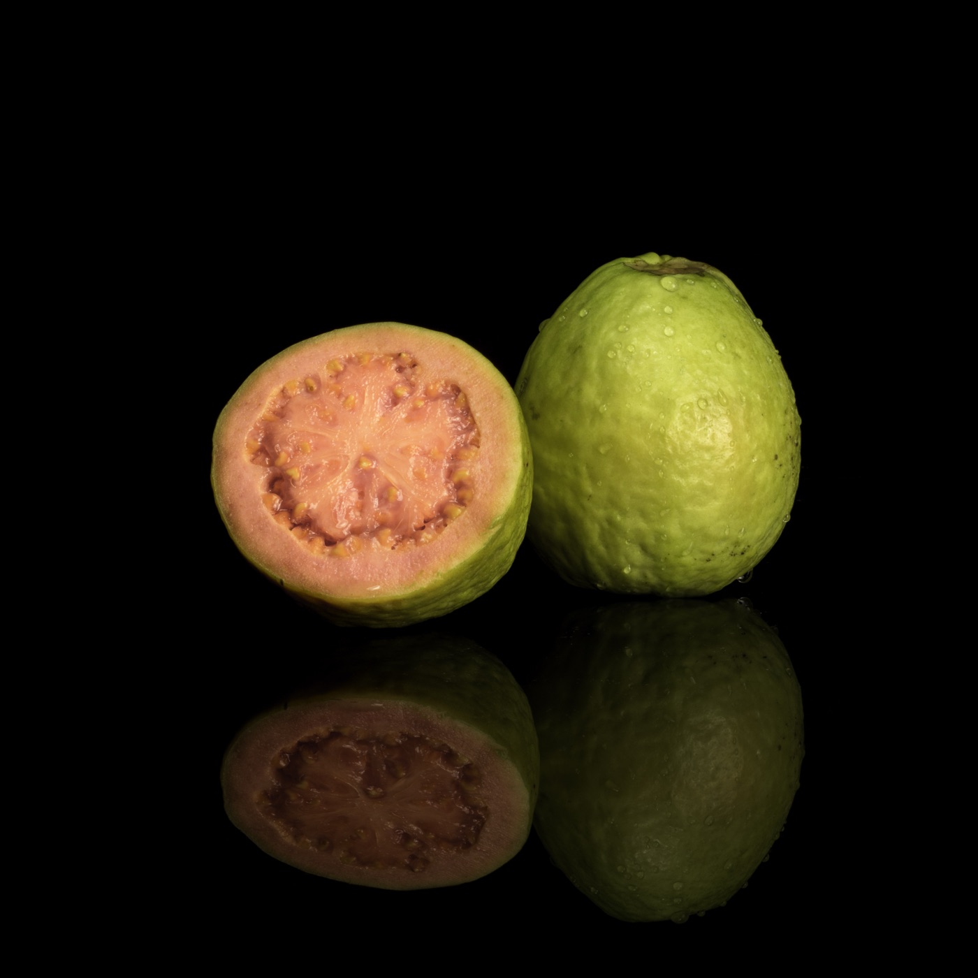 Whole and halved pink-fleshed guava