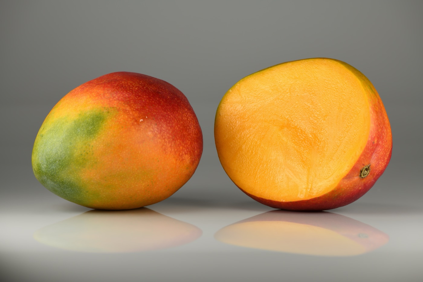 Whole and halved red-yellow mango
