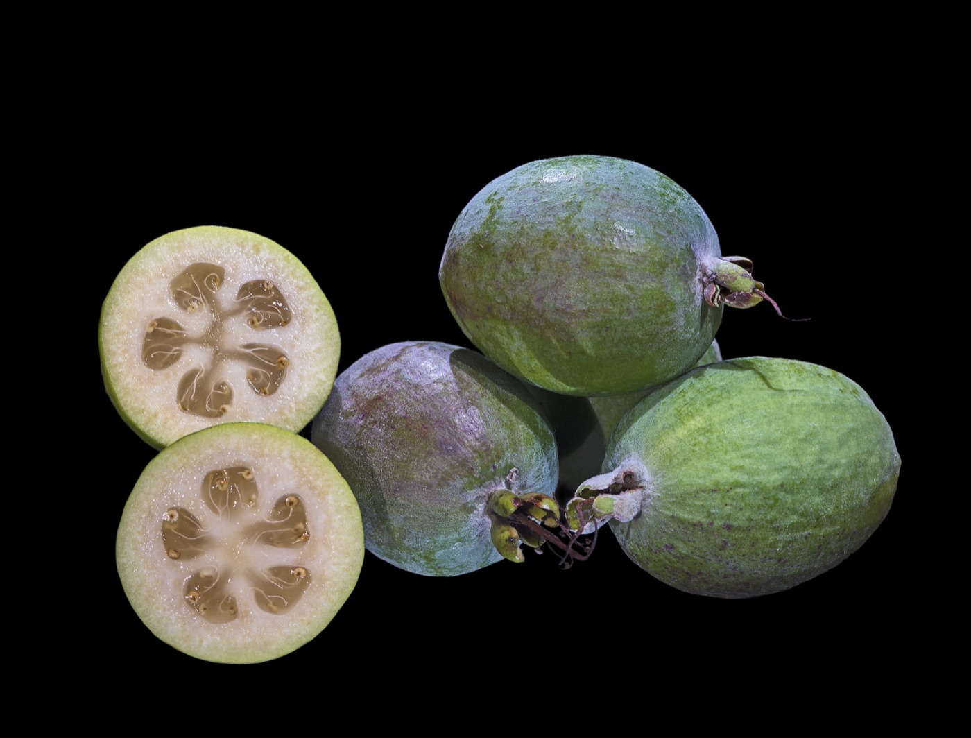Green feijoa fruit, whole and cut in half