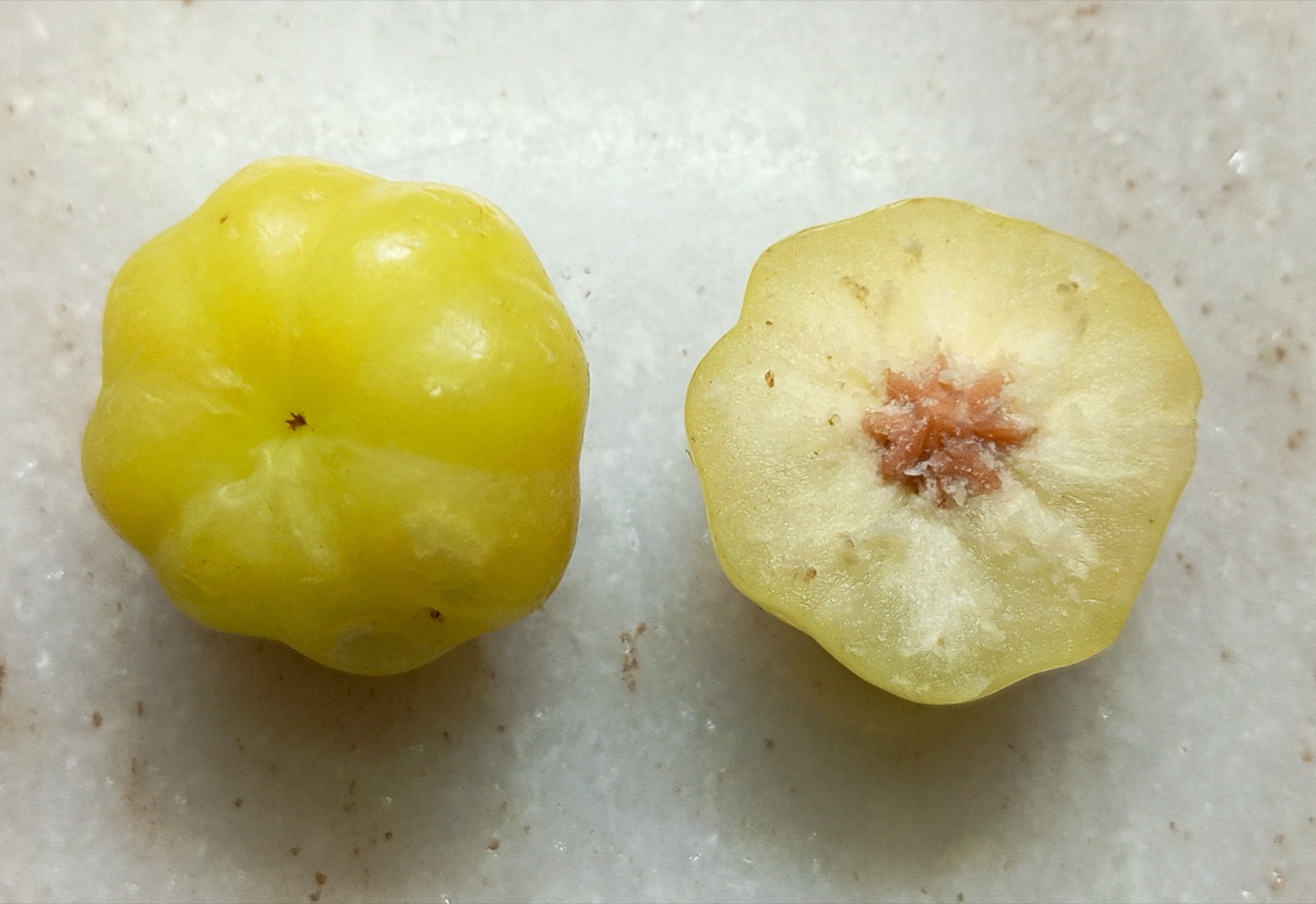 Whole and halved pale yellow star gooseberry fruit